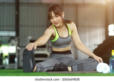 Close-up Attractive Millennial Fitness Woman Stretching Her Legs For Ready To Workout At The Gym. Warmup And Cool Down.