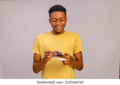 A closeup of an attractive young black man smiling while counting the paper bills in his hands