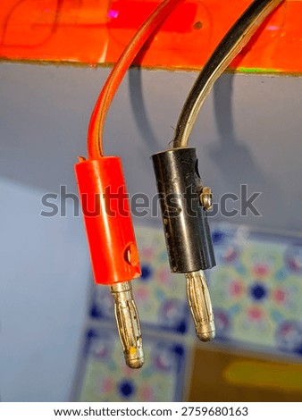 Close-up of an audio cable featuring red and black connectors, commonly used for sound equipment and hi-fi systems, showcasing the wire and plug details.