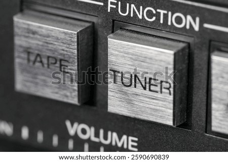Close-up of an audio system control panel. The details show the square buttons for function selection, such as tape, tuner, or volume.   