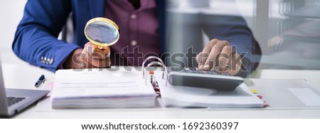 Closeup Of Auditor Scrutinizing Financial Documents At Desk In Office