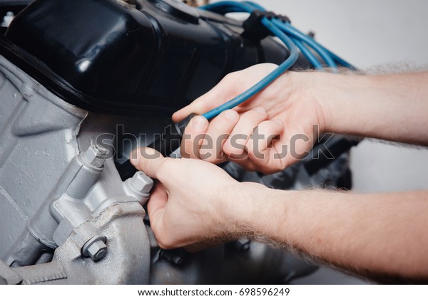 A close-up of an auto mechanic smiling repairs\
the engine of a lorry or bus replacement of a candle, a concept\
repair in a garage, a\
workshop.