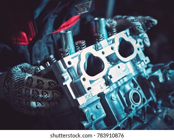 Closeup of an auto mechanic working on an automobile engine. Installing the intake manifold on the opposing engine.