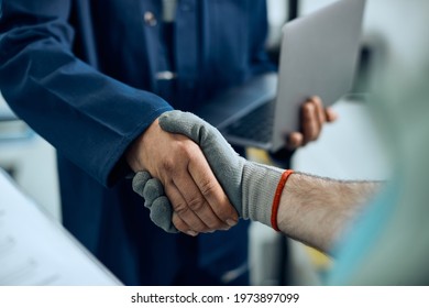 Close-up of auto repairman greeting workshop manager and handshaking with him at repair shop.  - Shutterstock ID 1973897099