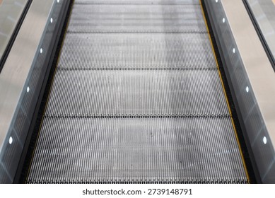 Close-up at automatic escalator pathway during it moving. Transportation equipment with object, selective focus.
