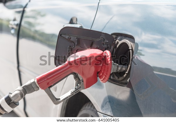 Close-up a automatic fuel nozzles filling into
car tank. Gas pump nozzle in fuel tank of blue car at gas station
in Texas, America. Auto shut-off gas nozzle refilling. Fuel,
energy, ecology
concept.