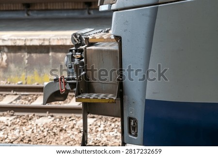 Close-up of an automatic train coupler and technical steps on a modern passenger train.