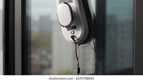 Close-up of automatic window cleaner robot. Working on residential window. Simplicity and convenience of window cleaning.