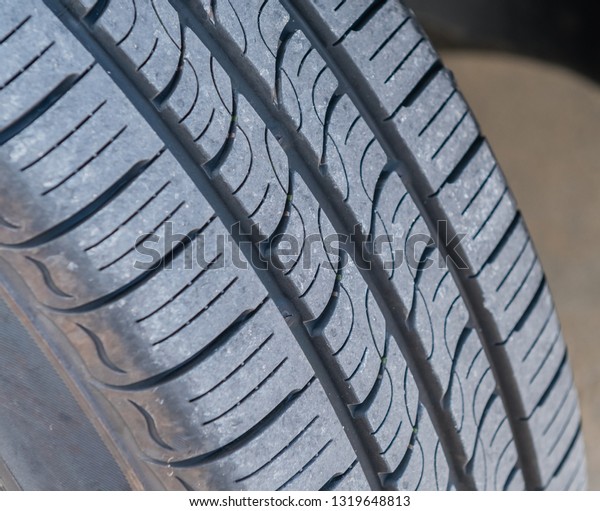 Closeup of automobile tire tread of new tire on\
sunny day.