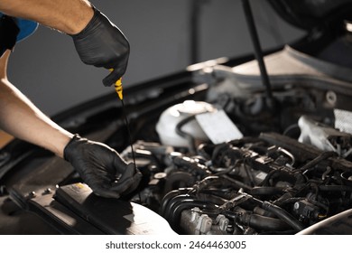 Close-up of automotive mechanic checks the oil level on the car engine dipstick. Car oil quality. Inspection of the engine and checking motor oil level. Man checks the car oil level with dipstick. - Powered by Shutterstock