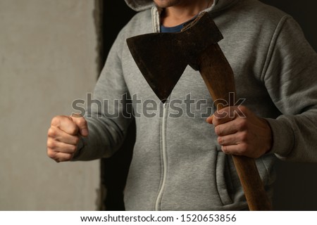 Close-up of the axe in the man's hand. The man with the axe