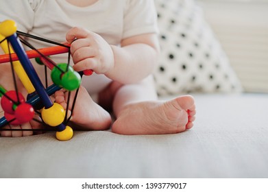 Close-up Of Baby Feet And Hands While Playing Indoors At Home With Colorful Sensory Toy