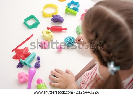 closeup baby girl playing with plasticine, play dough, playdough, mass for modeling, set for creativity