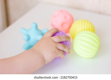 Closeup baby hand is touching tactile massage ball. Sensory or tactile activities. Children health. Massage textured balls for kids. Earlier development. Focus picked. - Powered by Shutterstock