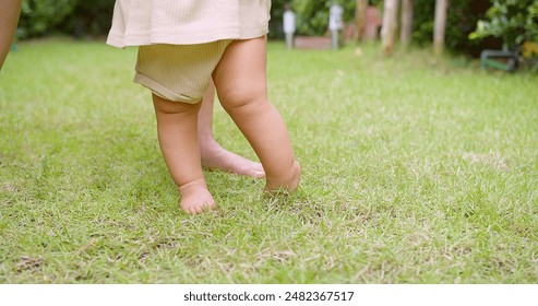 Close-Up of Baby's Legs Taking First Steps on Green Grass in Garden, Outdoor Toddler Exploration, Childhood Milestone, Natural Environment, Early Development, Innocence and Growth - Powered by Shutterstock