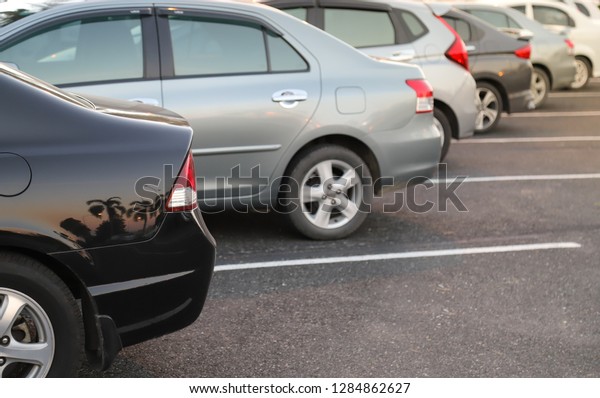 Closeup of back or rear side of black car with \
other cars parking in parking area with natural background in the\
evening of sunny day. The mean of simply transportation in modern\
world.
