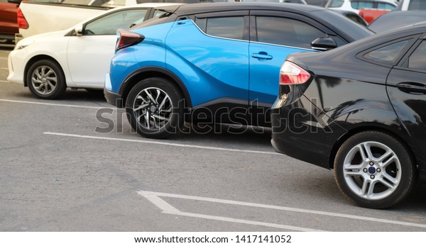 Closeup of back or rear\
side of black car and other cars parking in parking area with\
natural background in twilight evening. The mean of transportation\
in modern world.