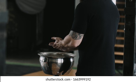 Close-up Back View Male Weight Lifter Athlete Applying Talc Powder Before Exercising In Large Hardcore Gym Hall.