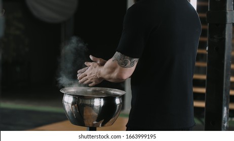 Close-up Back View Male Weight Lifter Athlete Applying Talc Powder Before Exercising In Large Hardcore Gym Hall.