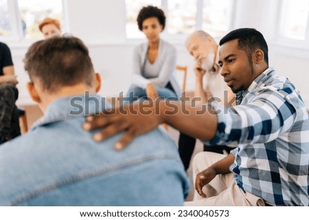 Closeup back view of unrecognizable sad man sharing life problem grief with multiracial people in modern mental health support group session in rehab center. Concept of mental health, psychotherapy.