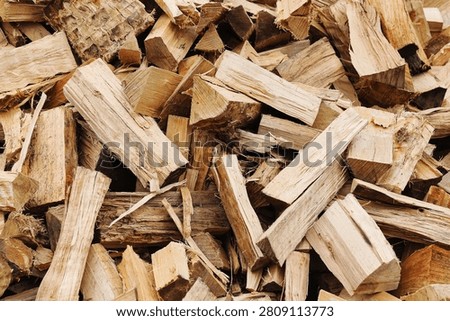Close-up background of freshly split firewood pieces showing rough wood grain and natural textures. Chopped logs prepared as heating fuel. Biomass energy and winter supply concept.