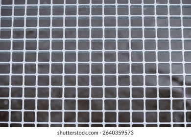 Close-up background of a metallic mesh structure with fine square pattern and spiderwebs. Transparent, high-resolution texture with parallel and perpendicular lines. Symmetrical and detailed.