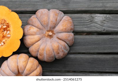 Close-up and background of nutmeg pumpkins. A pumpkin is cut open. The fruit lies on a background of old wood. There is space for text. - Powered by Shutterstock