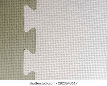 Close-up background texture of interlocking EVA foam puzzle mats in white and grey colors with a textured surface.