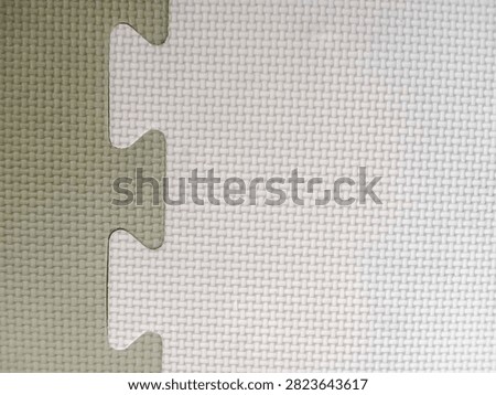 Close-up background texture of interlocking EVA foam puzzle mats in white and grey colors with a textured surface.