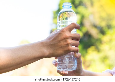 Closeup Backpacker Male And Female Hand Holding Plastic Water Bottle Outdoors.