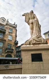 closeup backside view ancient statue of half naked woman against age-old building in old european city