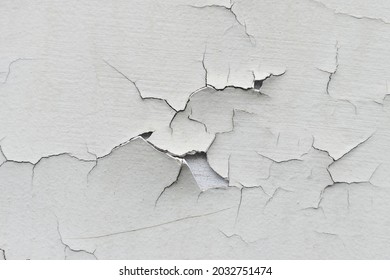 Close-up. Badly fixed building facade wall covered with cracks in stucco and paint. Missing patch of paint in the middle; crack with flappy peeling edges. - Shutterstock ID 2032751474