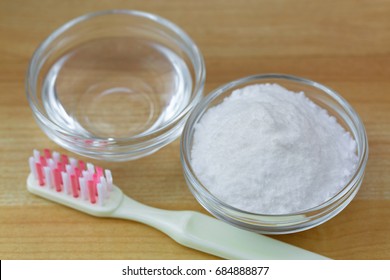 Closeup Of Baking Soda Powder Next To Vinegar, Toothbrush On Wooden Background. They Are Used As Powerful Cleaning Solution
