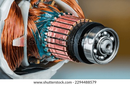 Closeup of ball bearing, commutator and rotor and stator inside electric DC motor. Copper wire with green epoxy in detail of machine to convert electrical energy into mechanical. Electronics industry.