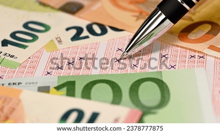 Close-up of a ballpoint pen tip making crosses on a lottery ticket surrounded by euro banknotes, with hope of winning the main prize