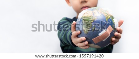 Closeup banner of a cute little asian boy a new generation presenting a damage globe full of bandages. Global warming, Climate change, Environmental problems. World pollution, Earth day, Net zero.