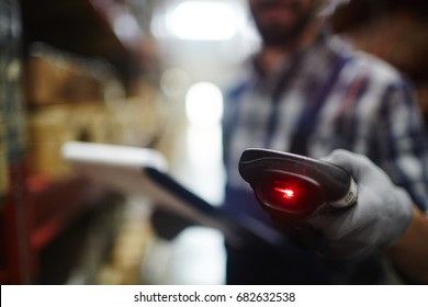 Closeup of bar code reader in hand of unrecognizable warehouse worker doing inventory of stock