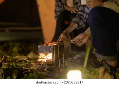 Close-up of barbecue meal grill in the wilderness of backpacker group. Grilled meals ready to eat for hiking groups, Camping in nature, Cooking at night with an atmosphere that is warm and inviting. - Powered by Shutterstock