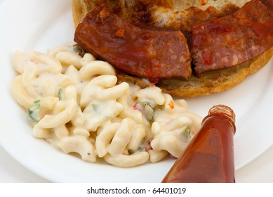 Closeup Of Barbecue Sausage Sandwich And Macaroni Salad With Bottle Of Louisiana Hot Sauce In Foreground.