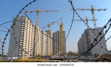 Close-up barbed wire and skyscraper construction on the background. Clear blue sky background.