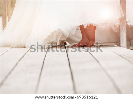 Closeup of bare feet of a bride on a wooden surface. Wedding background with free place for text.