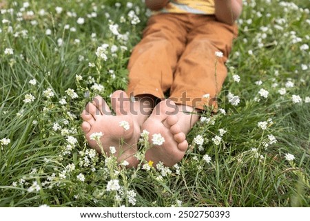 close-up of the bare feet of a child, with his toes spread out, sitting on a flowering meadow in a summer park. joy, relaxation, positive, happy childhood. Hello summer, energy of nature. Earth Day