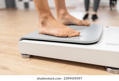 Close-up of bare feet stepping onto a modern body composition scale in a fitness or medical setting during Inbody test - Powered by Shutterstock