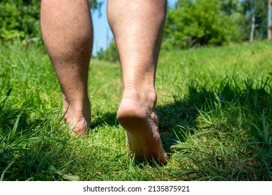 Close-up Of Bare Male Feet Walking On The Grass In The Village In Summer.