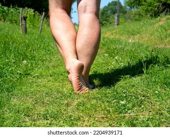 Close-up Of Bare Male Feet Walking On The Grass In The Village In Summer. Selective Focus