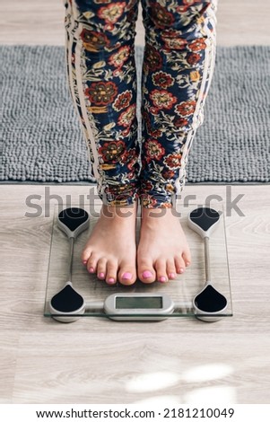 Closeup of barefoot woman using digital scales and checking her weight. Female feet step on floor scales. Concept of dieting, loosing weight and healthy lifestyle.