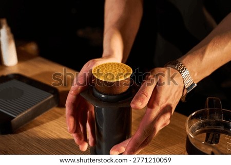 Close-up of barista ejecting a compressed coffee puck from an AeroPress after brewing