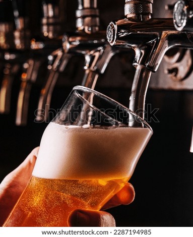 Close-up of barman hand at beer tap pouring a draught lager beer