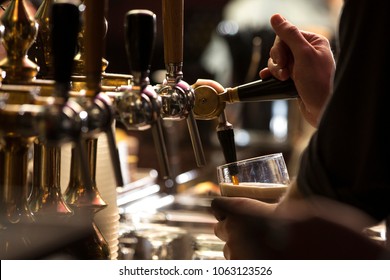 closeup of a bartender pouring a dark stout beer in tap with subject and focus on the right - Shutterstock ID 1063123526