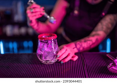 Close-up of a bartender preparing a margarita cocktail adding ice in the counter of a bar with neon lights - Powered by Shutterstock